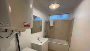 A compact bathroom with a sink, mirror, and bathtub. - Agréable logement 8 personnes (Chalon-sur-Saône)