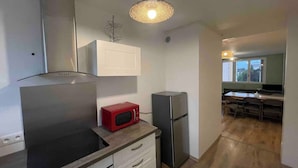 A compact kitchen with a microwave, refrigerator, and a built-in oven. - Agréable logement 8 personnes (Chalon-sur-Saône)