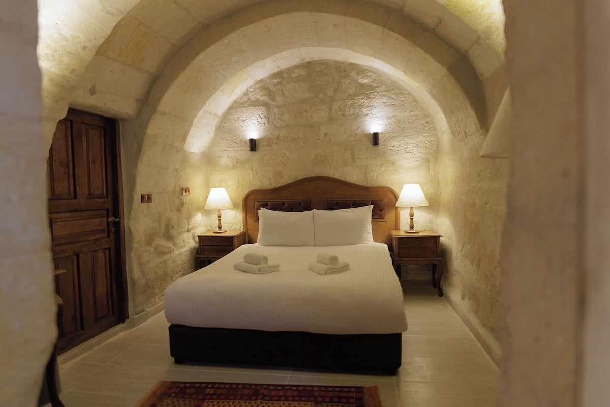 Ein Schlafzimmer mit einer Gewölbedecke, einem Holzbett, zwei Nachttischlampen und einem Nachttisch.