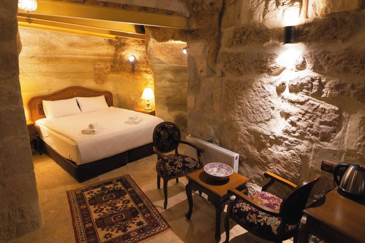 Ein gemütliches Zimmer mit einem Bett, einem Sessel, einem Tisch und einer Heizung.