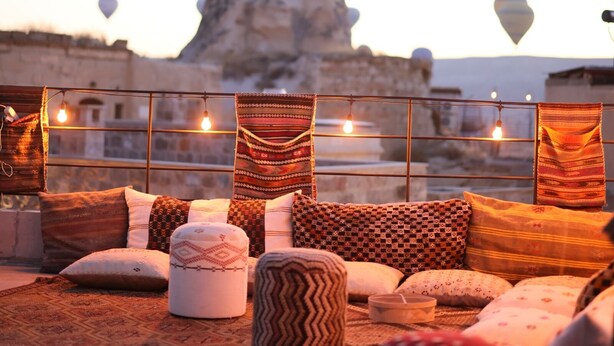 A rooftop seating area with patterned cushions and a view of a mountain. - Memory Cave House (Nevsehir)