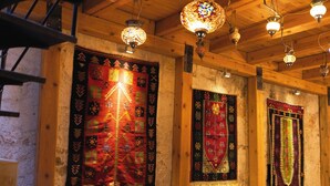 A cozy room with wooden beams, a fireplace, and three chairs around a coffee table. - Memory Cave House (Nevsehir)