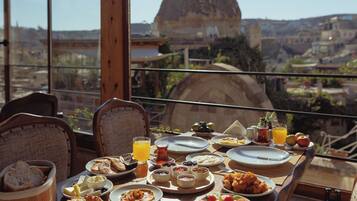 Una mesa de comedor con diferentes platos y vistas a una montaña.