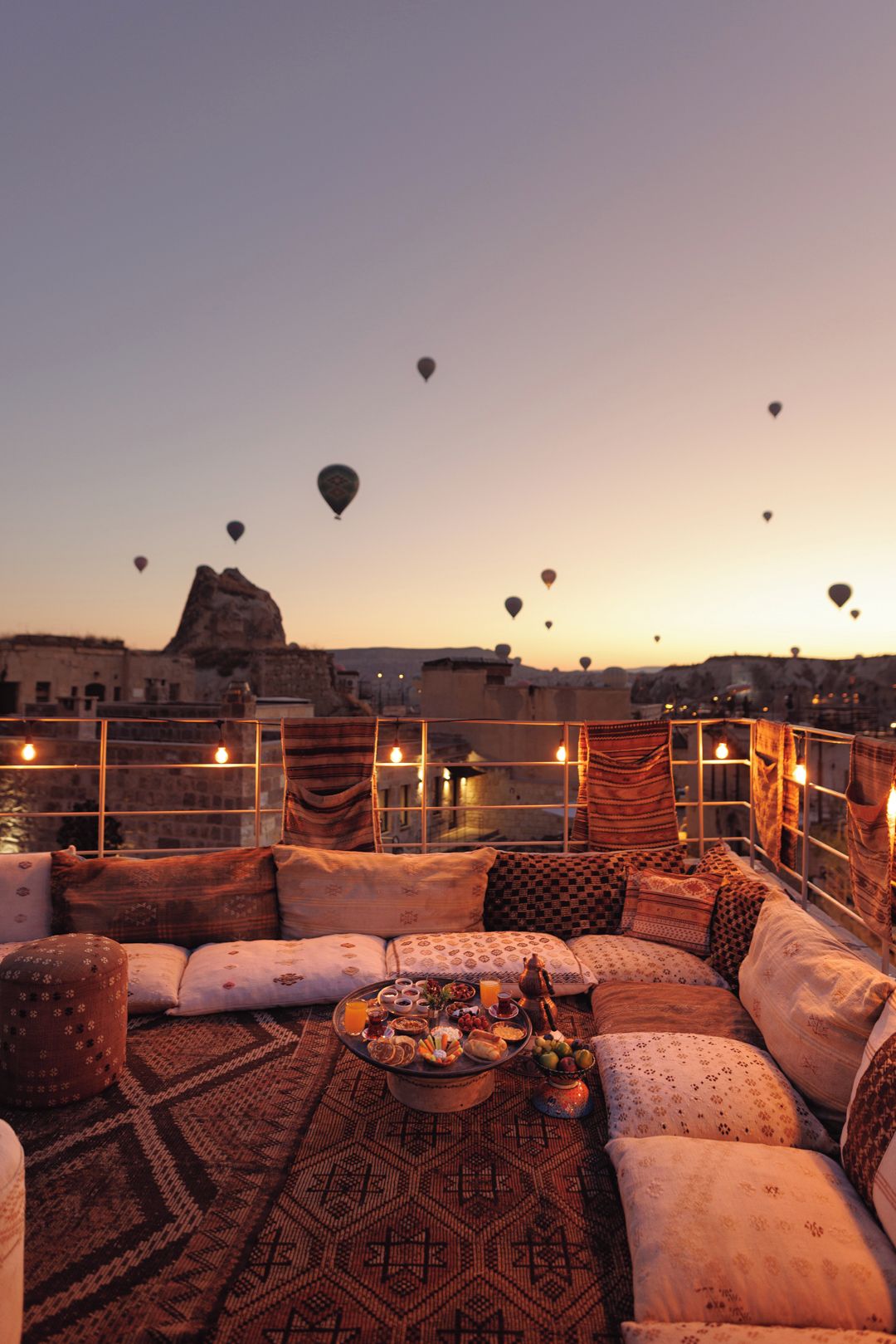 A cozy seating area with a view of hot air balloons and a distant rock formation.