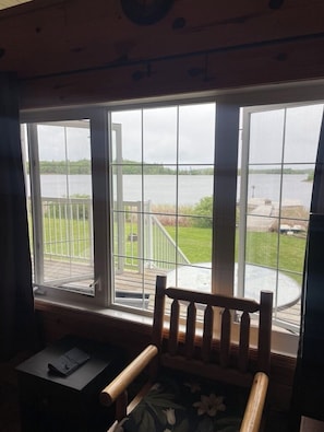 Una habitación con un ventanal grande con vistas a una terraza y un cuerpo de agua.