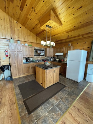 Eine Holzhütte mit einer Kücheninsel, Holzschränken, einem Einbauofen und einem Kühlschrank.