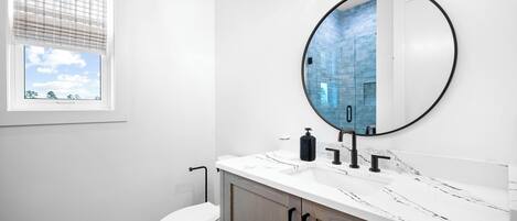 Ein modernes Badezimmer mit Toilette, Waschbecken und Spiegel.