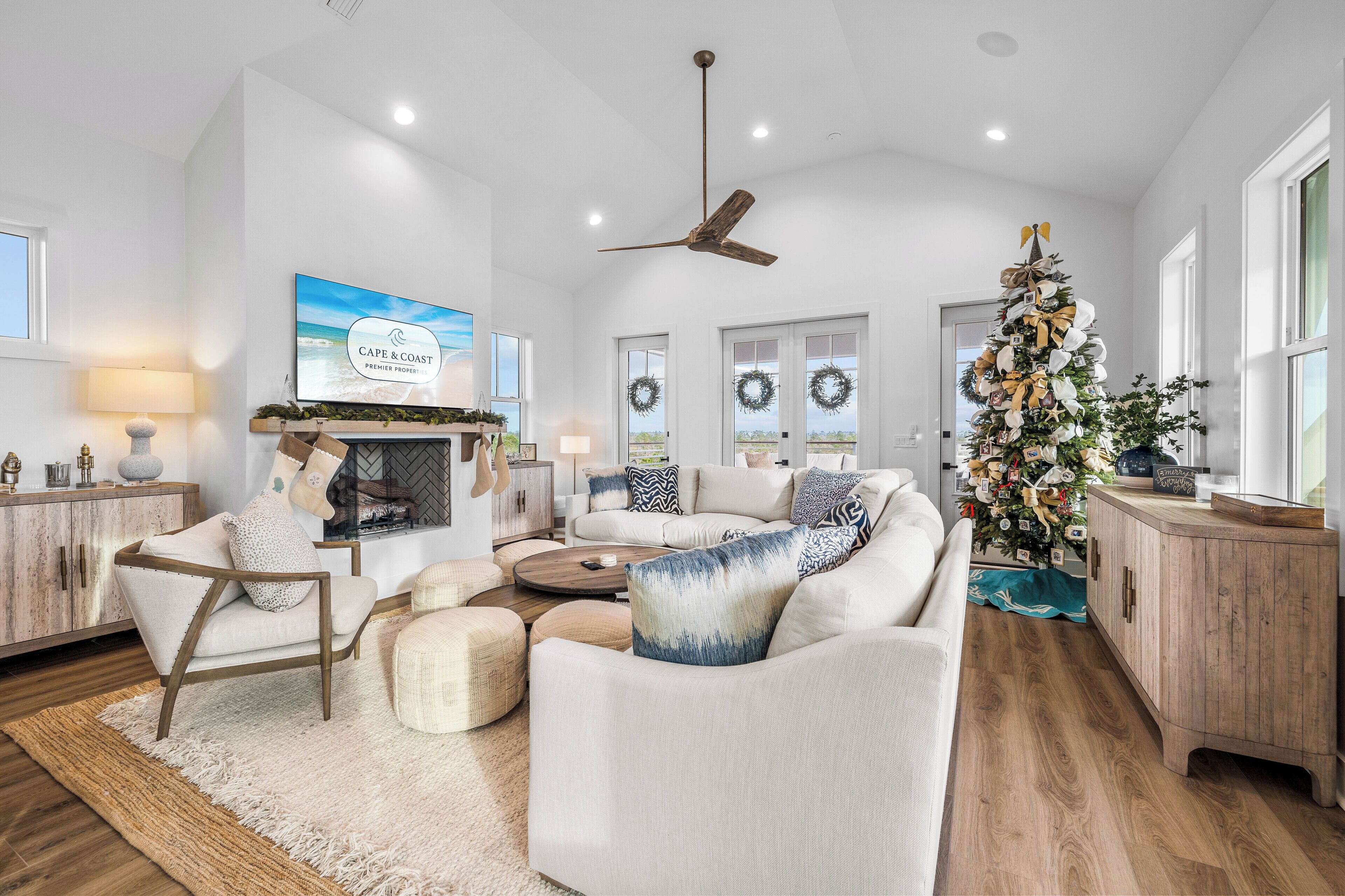 A spacious living room with a fireplace, a large Christmas tree, and a ceiling fan.