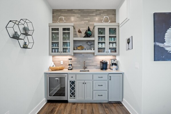 A modern kitchen with light grey cabinets, a built-in dishwasher, and a brick backsplash.