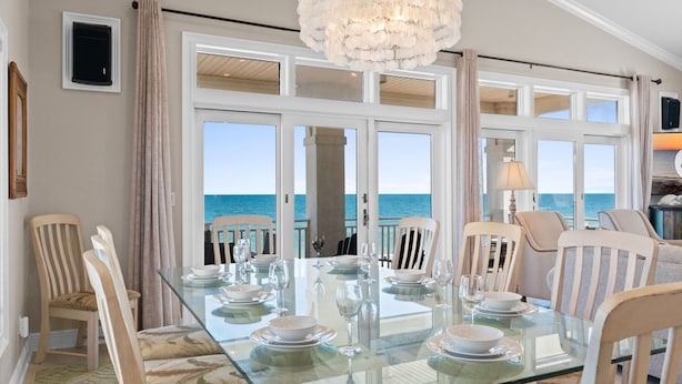 A dining area with a glass table set for six, overlooking the sea. - Turtle Tracks: Beachfront, East End, Pet Friendly, Sunset Beach (St. George Island)