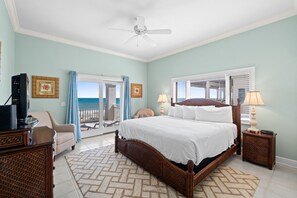 A bedroom with a bed, a television, a chair, a nightstand, and a view of the outdoors. - Turtle Tracks: Beachfront, East End, Pet Friendly, Sunset Beach (St. George Island)