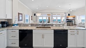 A spacious kitchen with a large island, white cabinetry, and a view to the outside. - Turtle Tracks: Beachfront, East End, Pet Friendly, Sunset Beach (St. George Island)
