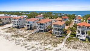 A coastal resort with beachfront villas featuring balconies, a sandy beach, and a view of the ocean. - Turtle Tracks: Beachfront, East End, Pet Friendly, Sunset Beach (St. George Island)