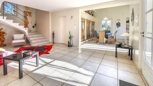 Un salón espacioso con una escalera, comedor y vistas al exterior.