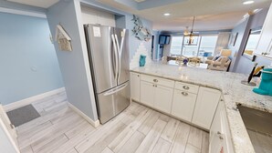 Une cuisine moderne dotée d’un réfrigérateur en acier inoxydable, de meubles blancs et d’un plan de travail en granit.