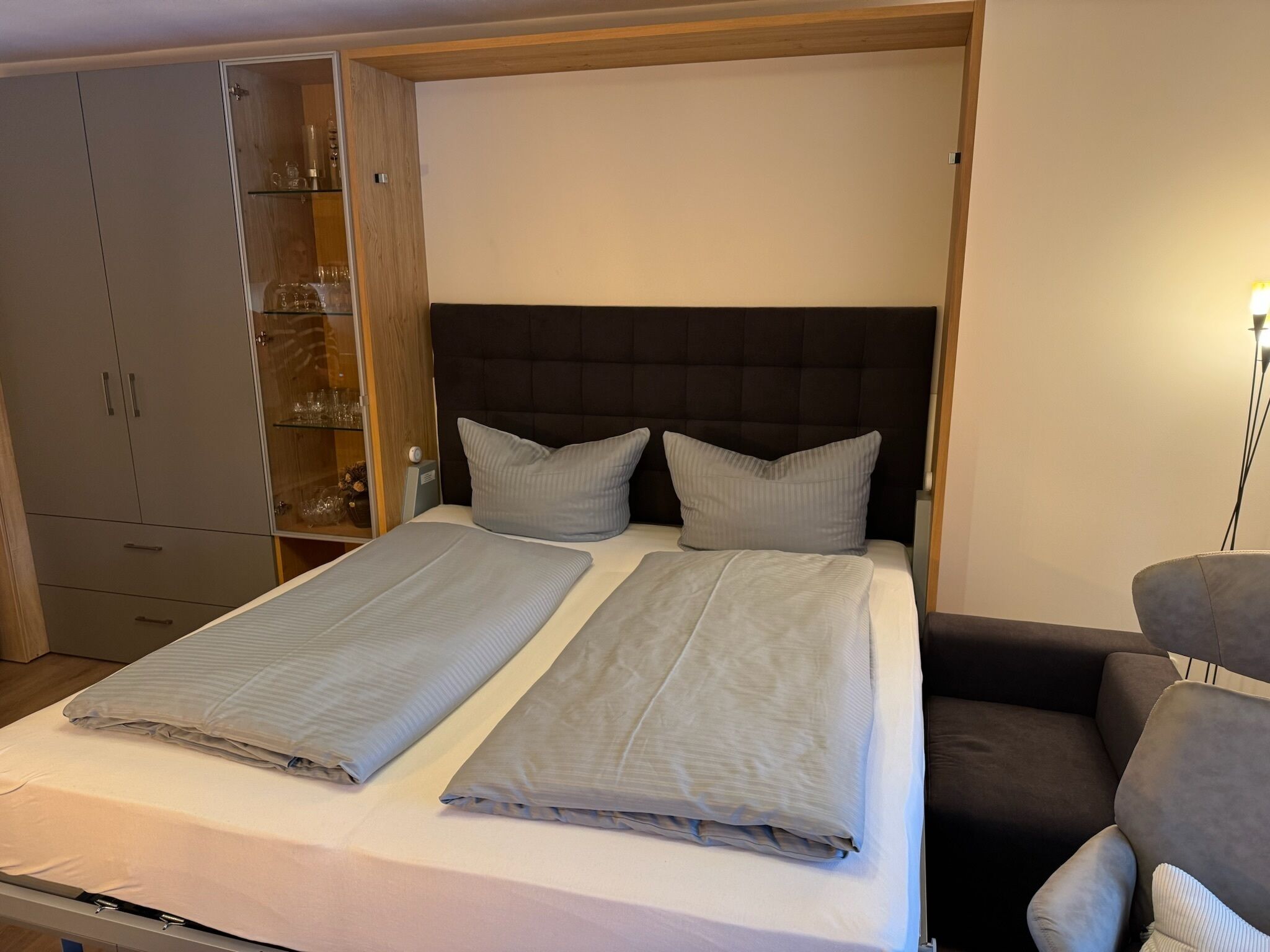 Un lit double avec deux oreillers, une table de chevet, une armoire et une chaise.
