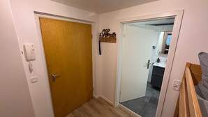 A hallway with a wooden door, a white door, and a small sign above the white door.