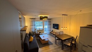 A modern living room with a sofa, coffee table, and dining area.