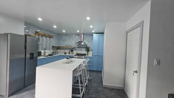 A modern kitchen with a central island, stainless steel appliances, and blue cabinets.