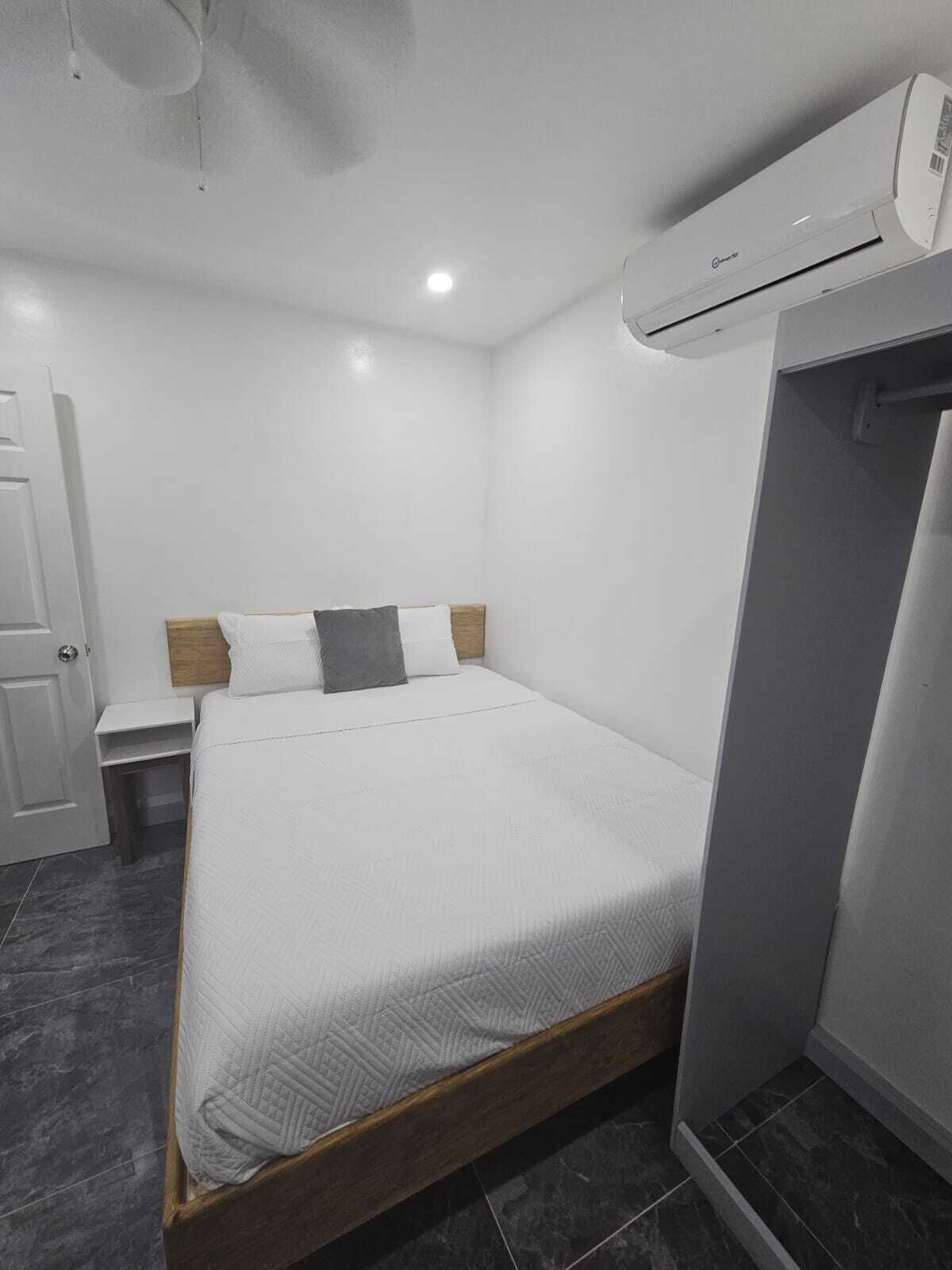 Ein modernes Hotelzimmer mit einem Einzelbett, einem Nachttisch, einem Kleiderschrank und einer Klimaanlage.