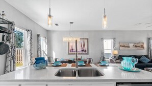 A modern kitchen with a central island, stainless steel appliances, and a dining area with a table set for four. - Hilltop Manor-4 Bedrooms 2 1/2 Bathrooms *Sleeps 10* Spring open! (Panama City Beach)