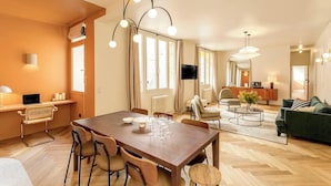Amplia sala de estar con una mesa de comedor de madera, múltiples opciones de asientos y una lámpara de araña moderna.