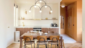 Una cocina moderna con una isla central, un comedor con seis sillas y una lámpara colgante sobre la isla.