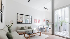 A modern living room with a sofa, coffee table, and a dining area with chairs and a table. - MOT Santa Fe 5164 (Buenos Aires)