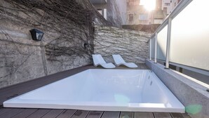 A spa area with a white hot tub, a stone wall, and a glass railing. - MOT Santa Fe 5164 (Buenos Aires)