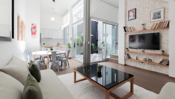 A modern living room with a glass door leading to a balcony, a flat-screen TV mounted on a wall, and a dining area visible through the glass door. - MOT Santa Fe 5164 (Buenos Aires)
