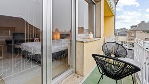 A balcony with a bed, a chair, and a table.