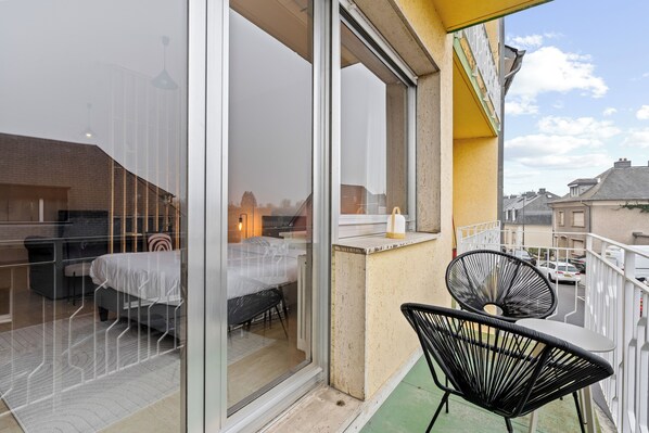 A balcony with a bed, a chair, and a table.