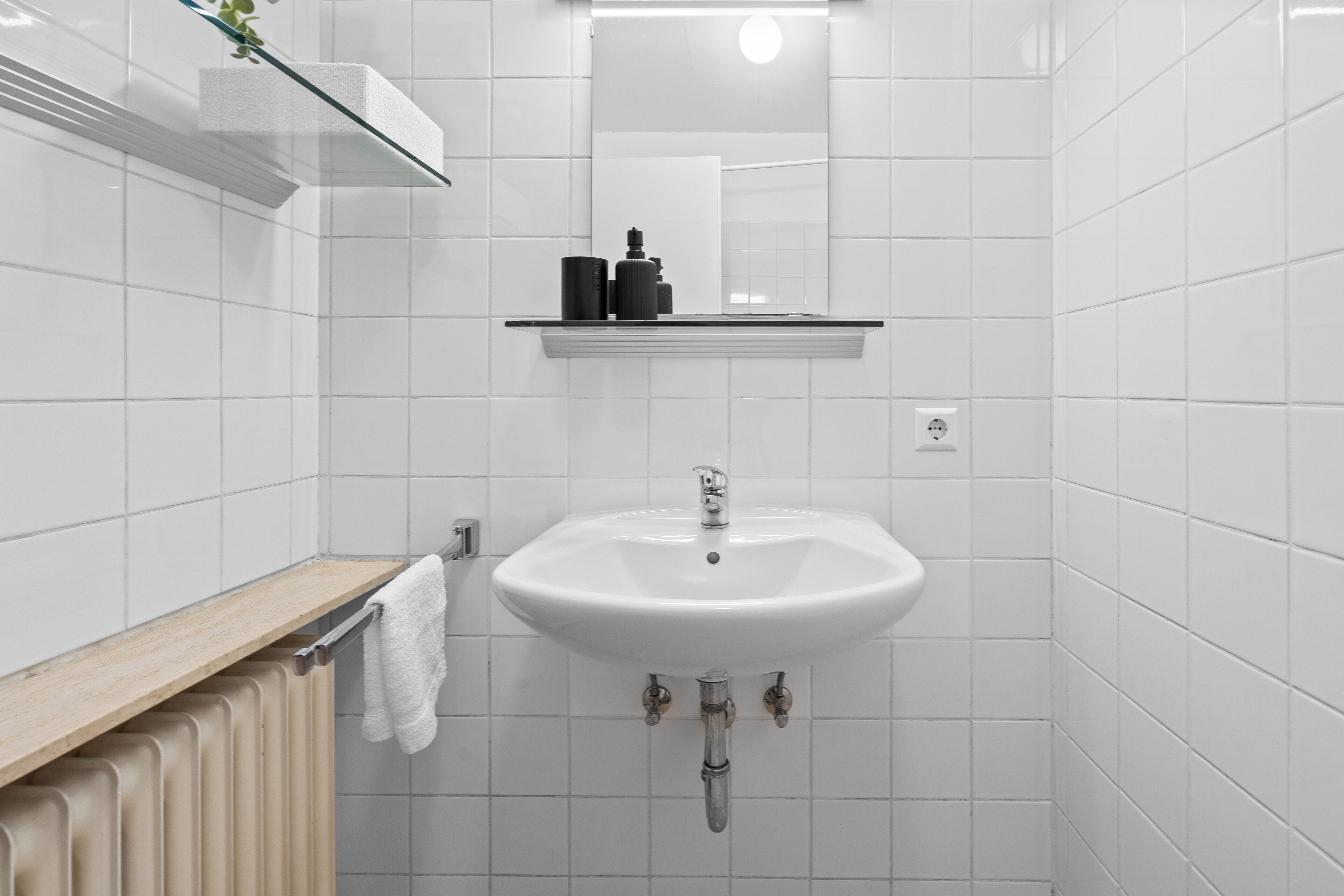 A bathroom with a white sink, a mirror above it, and a towel hanging on a rack.