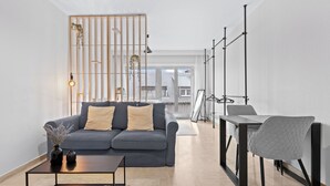 A modern living room with a grey sofa, a coffee table, and a dining area with a chair and table.