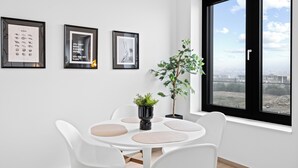 A modern dining area with a round table, white chairs, and a potted plant.
