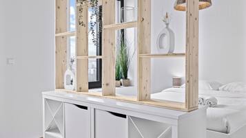 Une chambre moderne avec un lit blanc, une tête de lit en bois et une grande fenêtre.