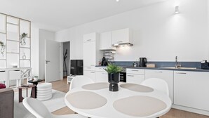 A modern kitchen with white cabinetry, a central island with seating, and a built-in stove.