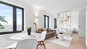 A modern living room with a dining area, large windows, and a view of the city.