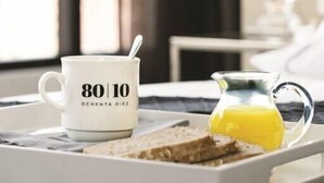A tray with a mug, toast, and a glass of orange juice on a bed. - Ochenta Diez by Wynwood House (Bogotá)