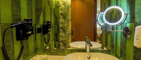 Une salle de bain équipée d’un grand lavabo, d’un miroir, d’une douchette à main et d’un distributeur de serviettes.