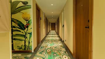 A hallway with a patterned carpet, wooden doors, and a mural of tropical plants on the wall.