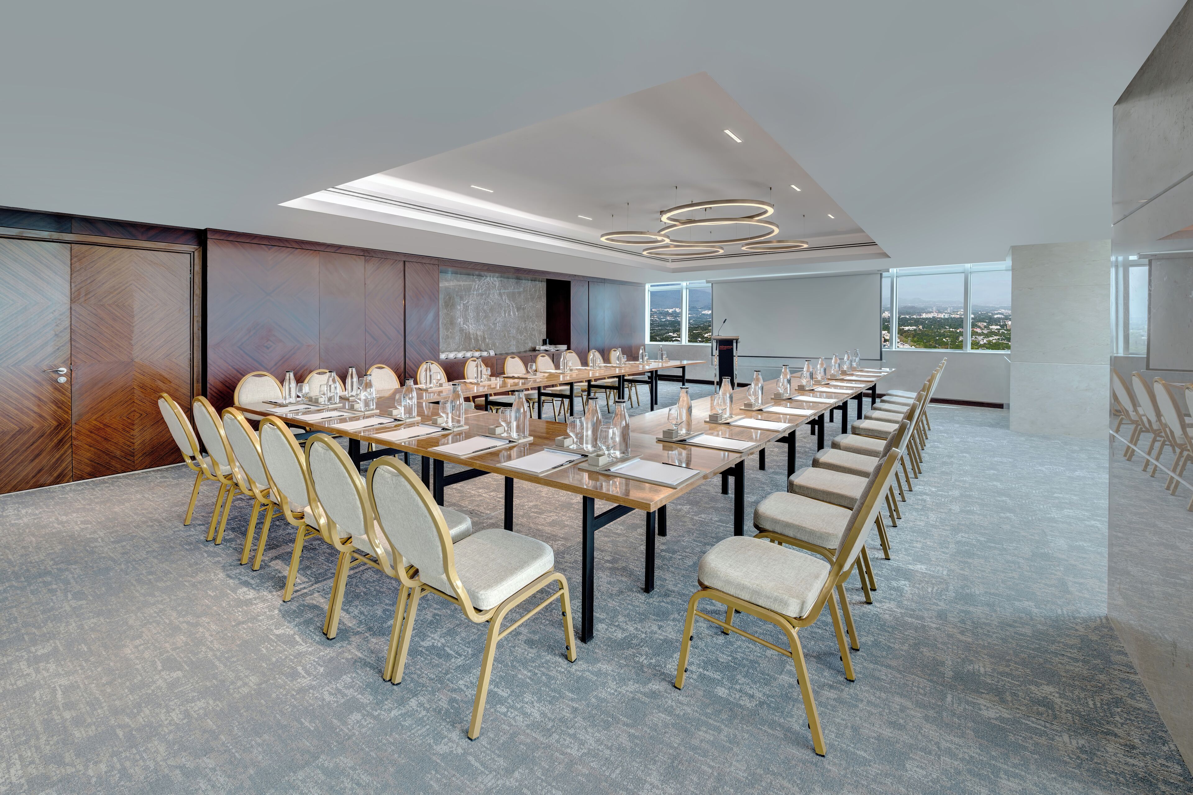A conference room with a long table, multiple chairs, and a large screen.