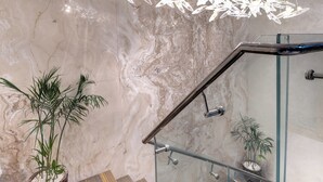A modern staircase with a glass railing, marble walls, and hanging light fixtures. - Movenpick Centaurus Islamabad (Islamabad)