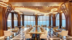 A modern dining area with a panoramic city view, featuring a geometric floor pattern and contemporary furniture. - Movenpick Centaurus Islamabad (Islamabad)