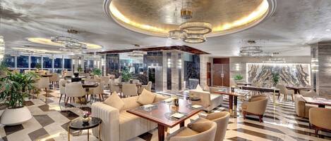 A spacious lobby with a checkered floor, multiple seating areas, and a large chandelier.