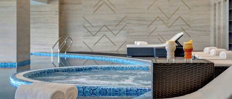 Zona de spa con jacuzzi, toallas y camilla de masaje.