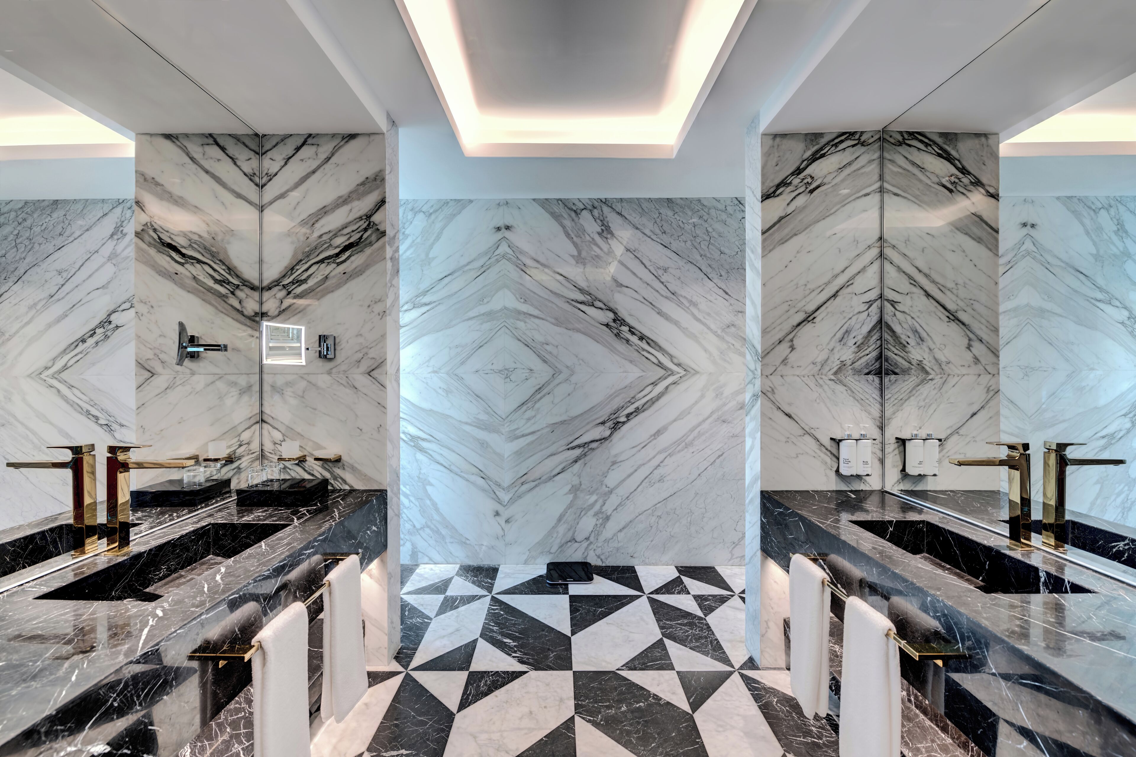 A modern bathroom with marble walls and a geometric tile floor.