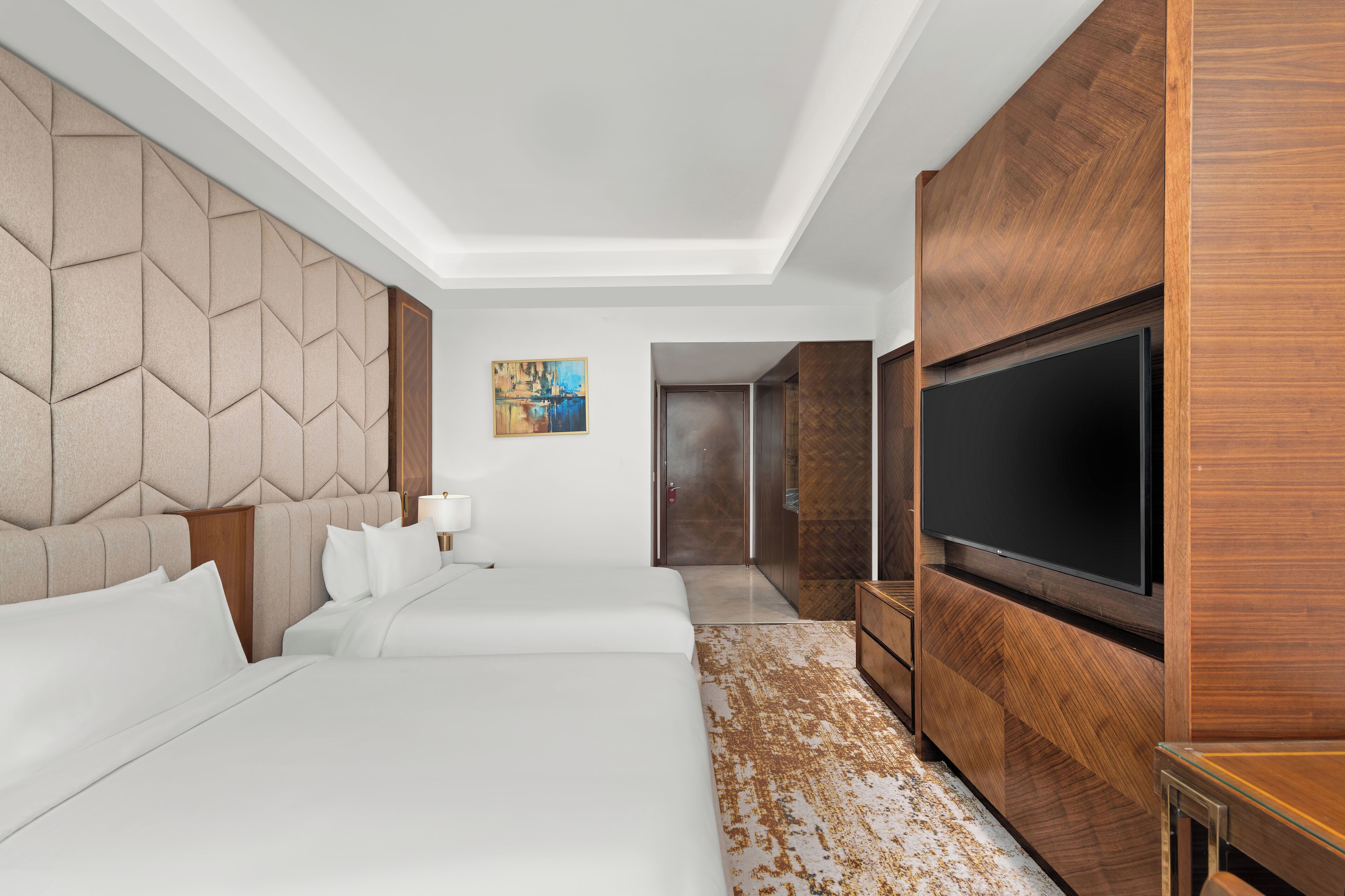 A hotel room with a large bed, a TV, and a wooden wardrobe.