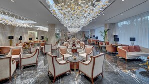 A spacious lobby with a high ceiling, chandeliers, and a variety of seating arrangements including sofas and armchairs. - Movenpick Centaurus Islamabad (Islamabad)