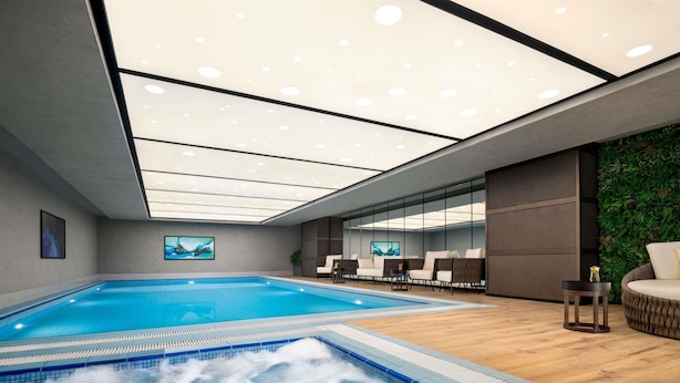 A modern indoor pool area with a hot tub, seating, and a green wall. - Novotel Residences Makkah (Makkah)